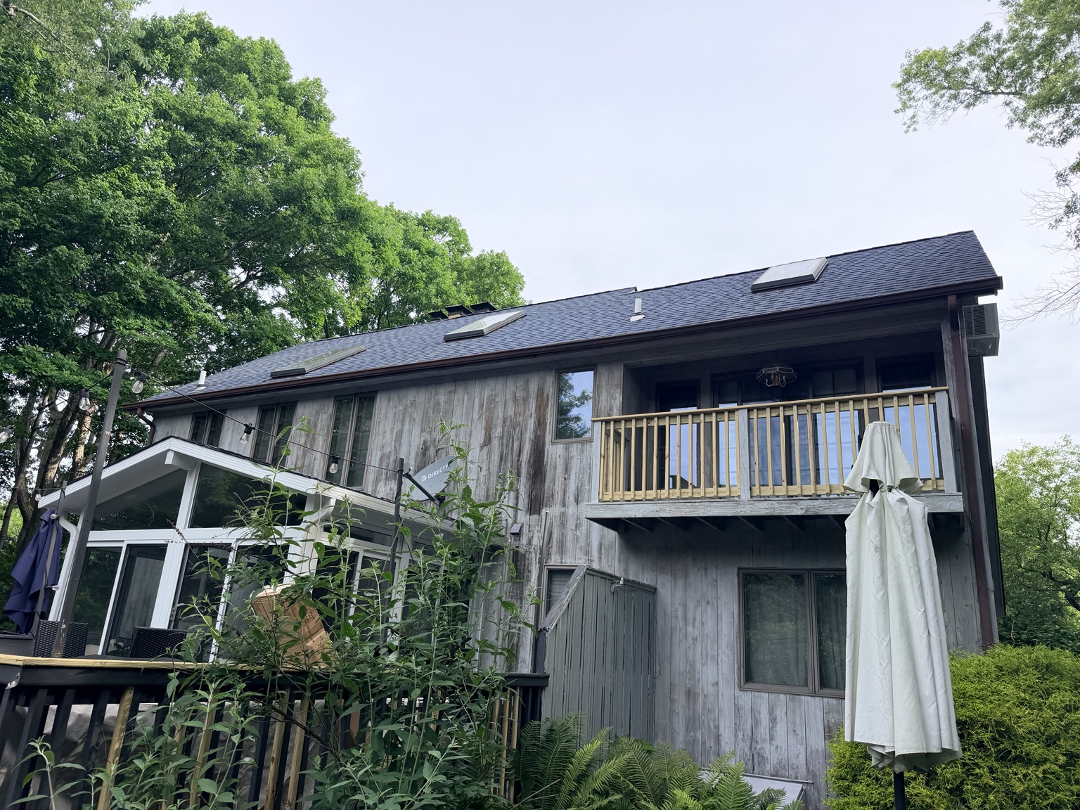 Weathered Long Island home before painting: faded and chalking siding, peeling white trim, mildew streaks under the gutters, dull front door.
