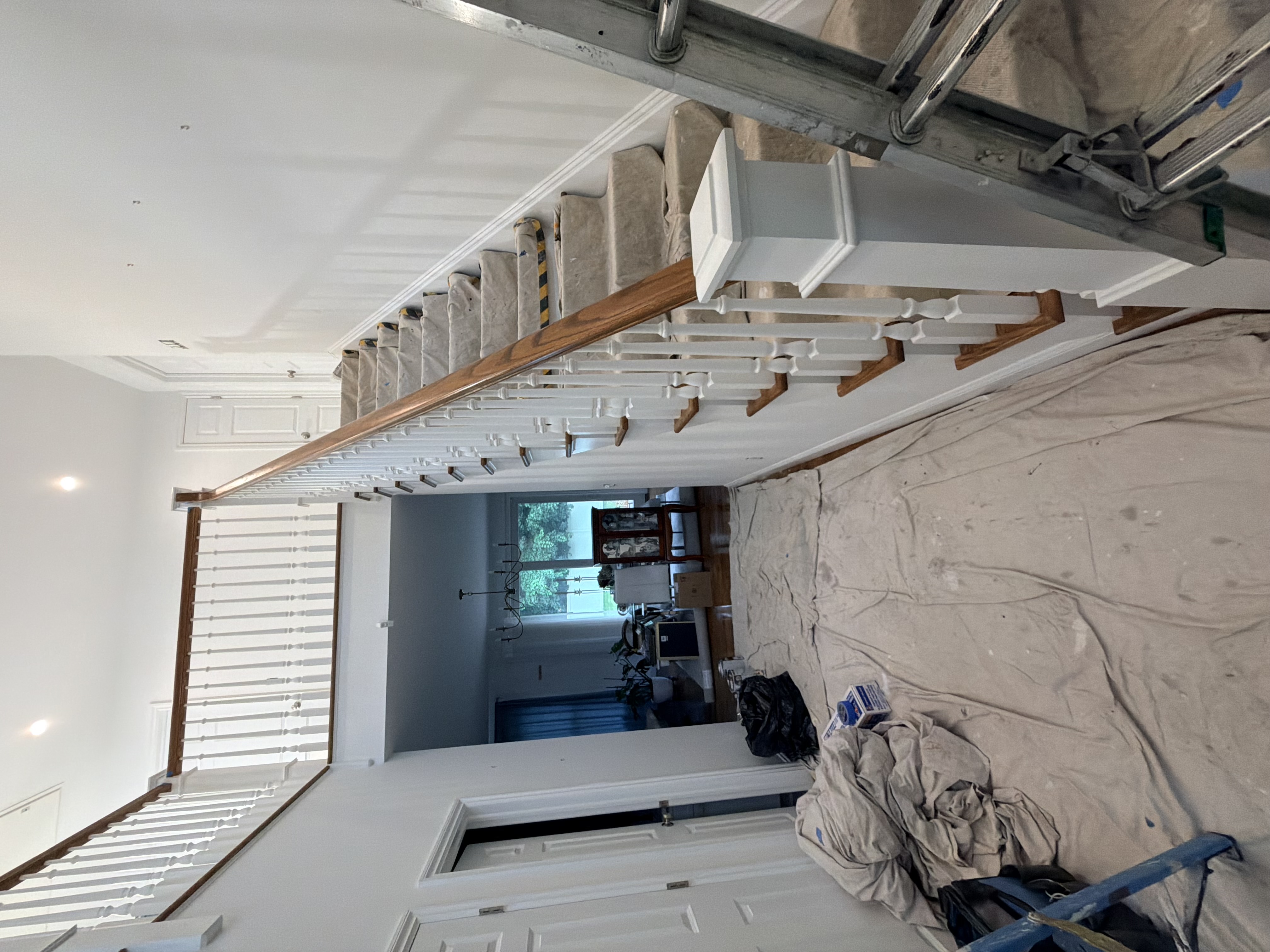 Dated living room before work: scuffed builder-beige walls, yellowed trim, visible patch marks, tired popcorn-adjacent ceiling.