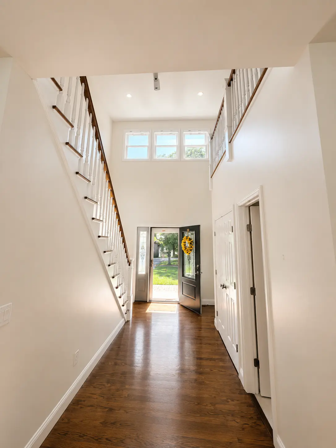 The same living room finished: smooth walls in a warm modern neutral, crisp bright-white trim and doors, clean ceiling, furniture back in place.