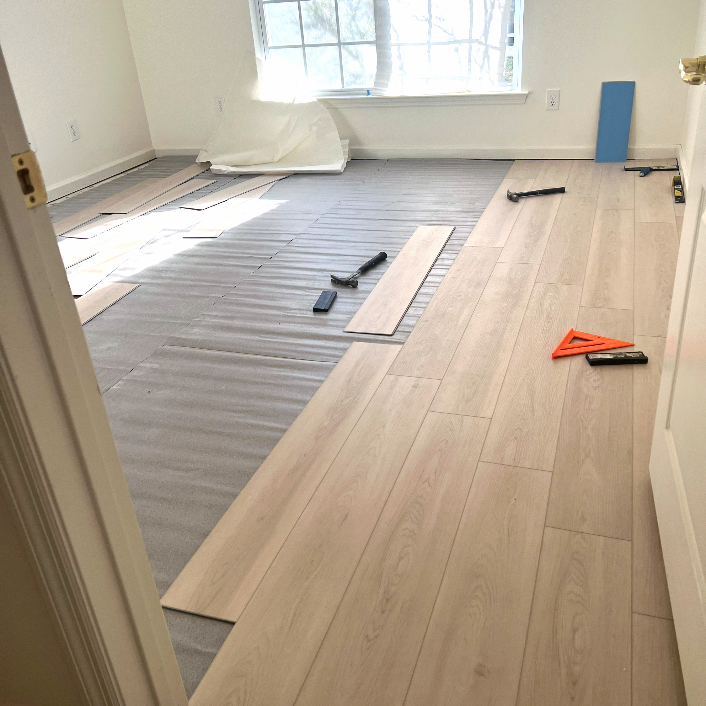 New luxury vinyl plank flooring running through a living room into a hallway, tight seams and clean transitions at the doorway.